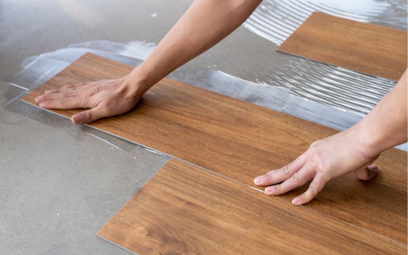 Bodenzubehör für perfekte Verlegung: im Bild wird das Verkleben von Bodenbelägen gezeigt – das passende Zubehör wie Kleber, Spachtel und Unterlagen sorgt für eine langlebige, stabile und saubere Bodenmontage 